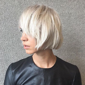 Modelo com cabelo loiro brilhante e franja reta.